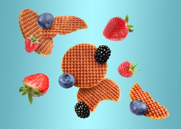 Image of Tasty Dutch waffles and fresh berries flying on light blue gradient background