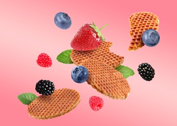 Image of Tasty Dutch waffles, fresh berries and mint flying on pink gradient background