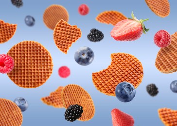 Image of Tasty Dutch waffles and fresh berries flying on blue gradient background