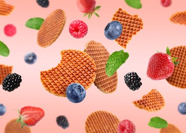 Image of Tasty Dutch waffles, fresh berries and mint flying on pink gradient background