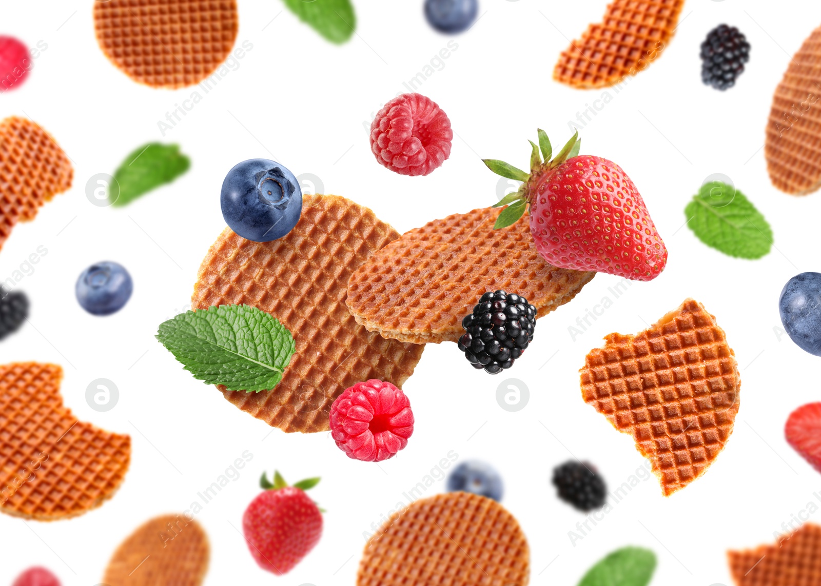 Tasty Dutch waffles, fresh berries and mint flying on white background Image of Tasty Dutch waffles, fresh berries and mint flying on white background