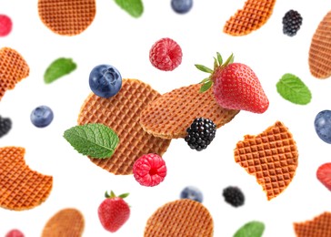 Image of Tasty Dutch waffles, fresh berries and mint flying on white background