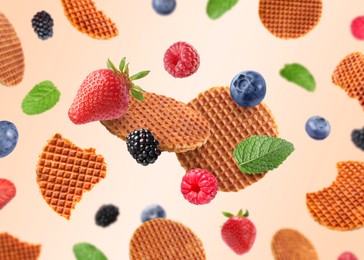 Image of Tasty Dutch waffles, fresh berries and mint flying on beige gradient background