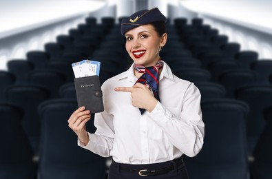 Image of Smiling stewardess pointing at passport with flight tickets in airplane cabin