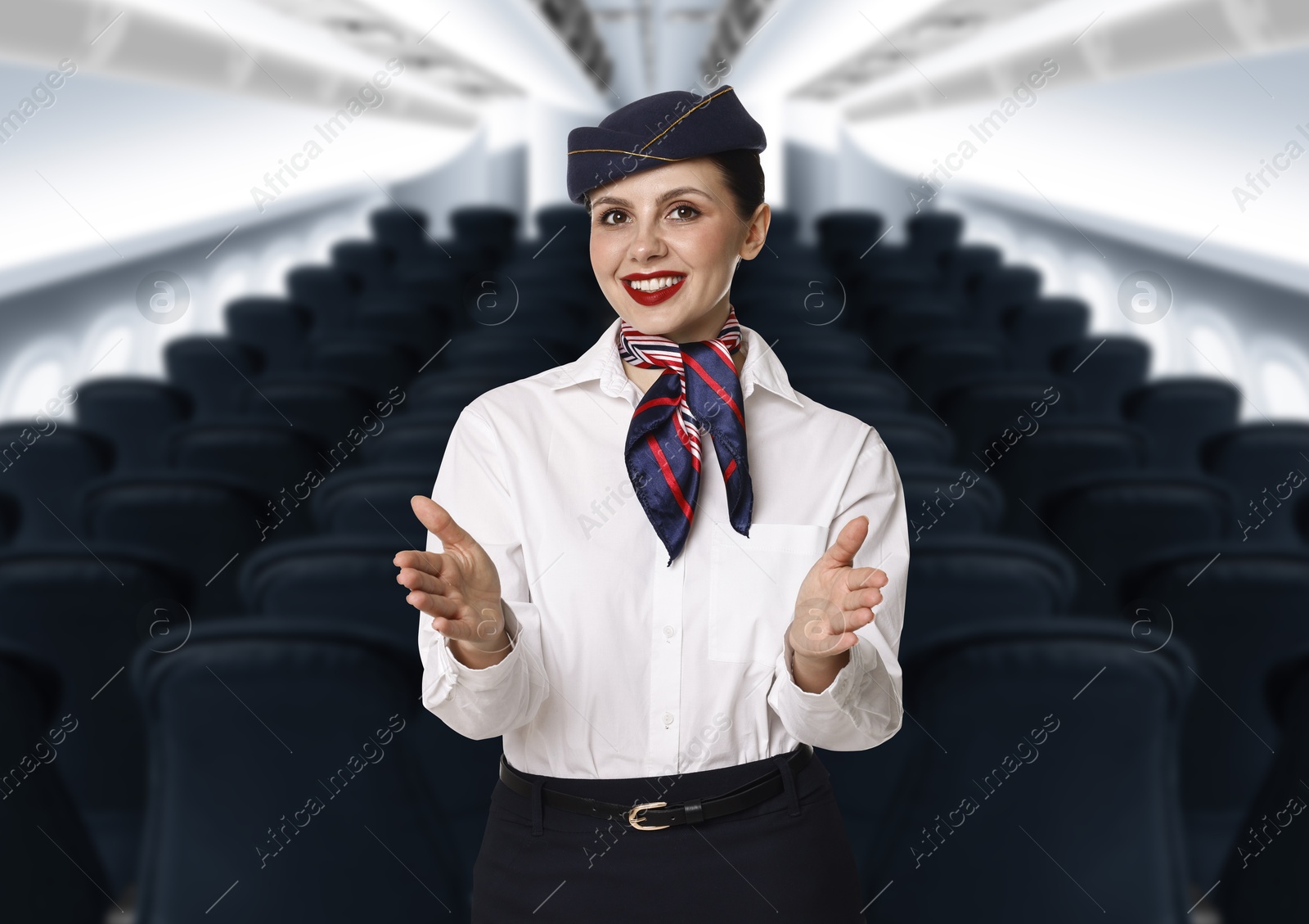 Smiling stewardess demonstrating safety instruction in airplane cabin Image of Smiling stewardess demonstrating safety instruction in airplane cabin