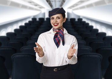 Image of Smiling stewardess demonstrating safety instruction in airplane cabin