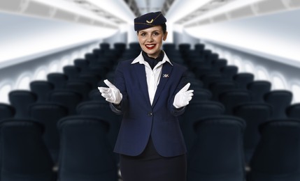 Image of Smiling stewardess demonstrating safety instruction in airplane cabin