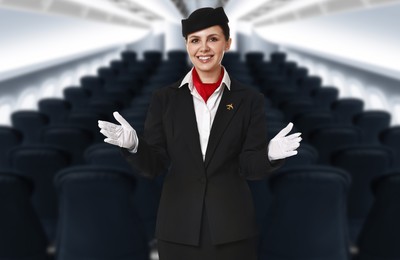 Image of Smiling stewardess demonstrating safety instruction in airplane cabin