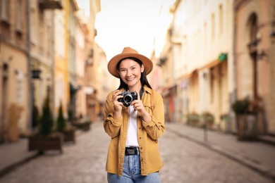 Image of Happy tourist with camera on city street