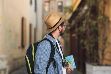 Image of Tourist with camera, backpack and map on city street