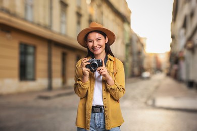 Image of Happy tourist with camera on city street