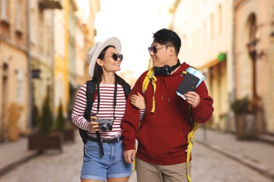 Image of Happy tourists with backpacks, flight tickets and camera on city street