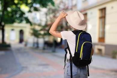 Image of Tourist with backpack on city street, back view. Space for text