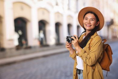 Image of Happy tourist with camera and backpack on city street. Space for text