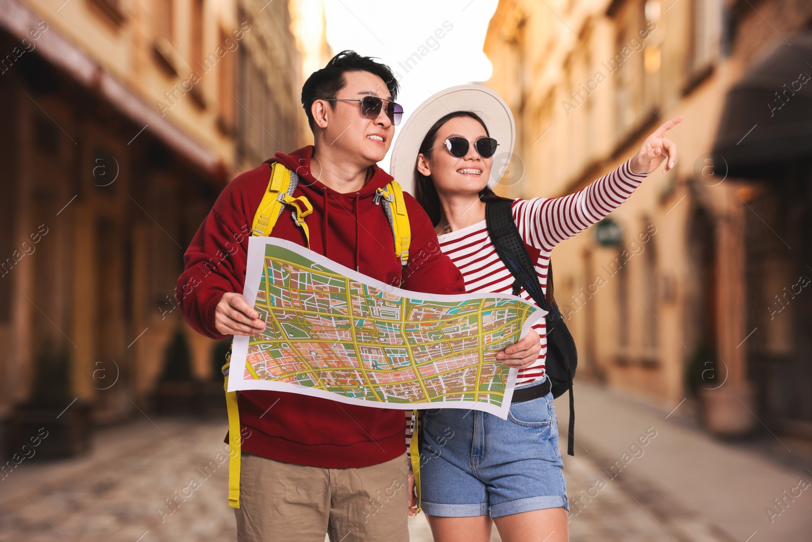 Happy tourists with map pointing at something on city street Image of Happy tourists with map pointing at something on city street