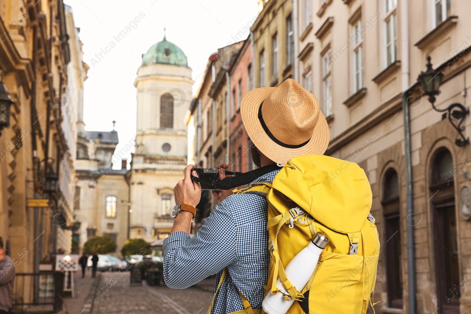 Tourist with backpack taking photo on city street, back view Image of Tourist with backpack taking photo on city street, back view