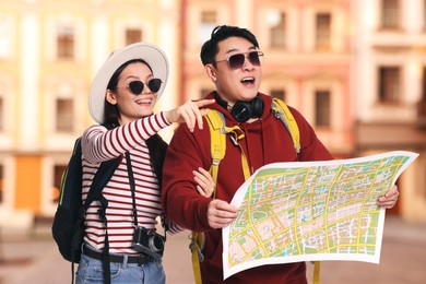 Image of Happy tourists with map pointing at something on city street