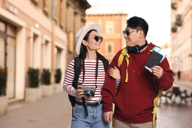 Image of Happy tourists with backpacks, flight tickets and camera on city street