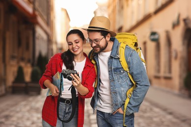 Image of Happy tourists with backpack and camera on city street