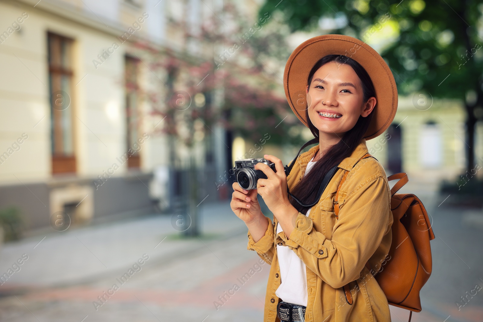 Happy tourist with camera and backpack on city street. Space for text Image of Happy tourist with camera and backpack on city street. Space for text
