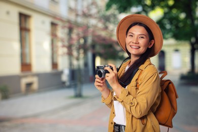 Image of Happy tourist with camera and backpack on city street. Space for text