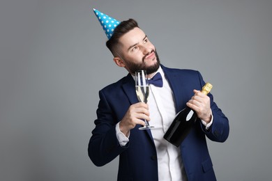 Photo of Happy Birthday. Handsome man with party hat and champagne on grey background