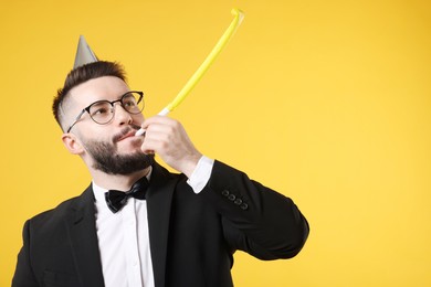 Photo of Happy Birthday. Handsome man with party hat and blower on orange background, space for text