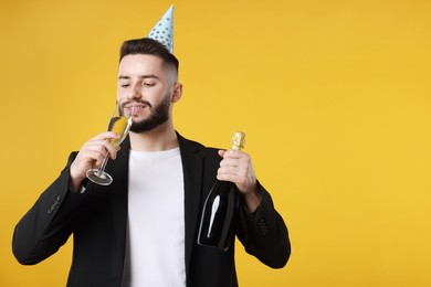 Photo of Happy Birthday. Handsome man with party hat and champagne on orange background, space for text