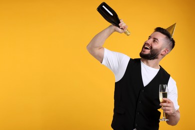 Photo of Happy Birthday. Handsome man with party hat and champagne on orange background, space for text