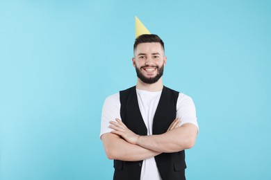 Photo of Happy Birthday. Handsome man with party hat on light blue background, space for text