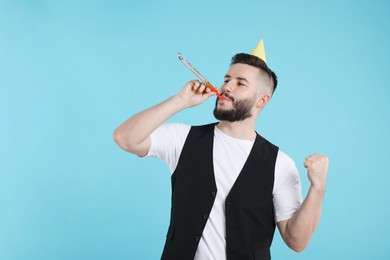 Photo of Happy Birthday. Handsome man with party hat and blower on light blue background, space for text