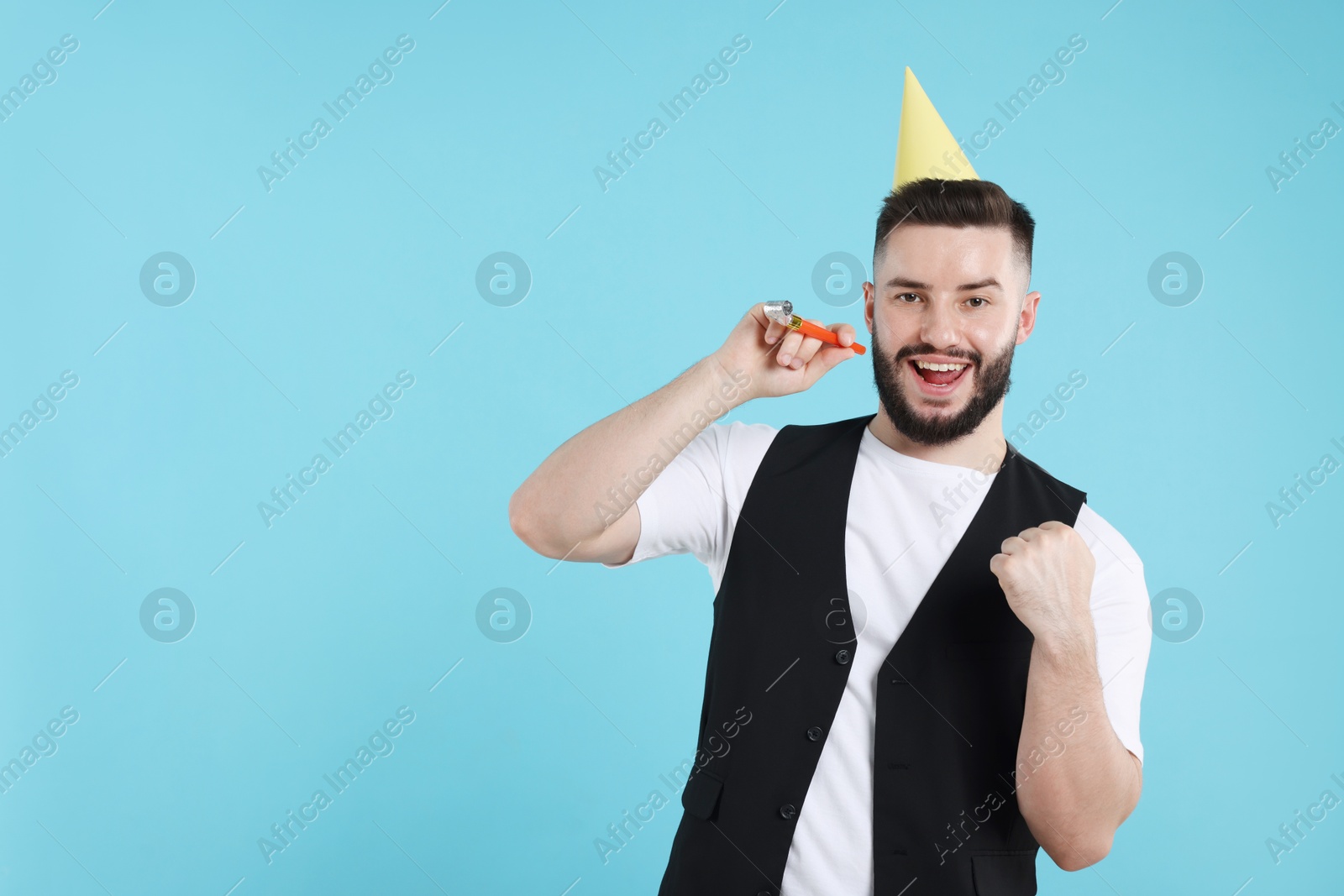 Happy Birthday. Handsome man with party hat and blower on light blue background, space for text Photo of Happy Birthday. Handsome man with party hat and blower on light blue background, space for text