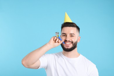 Photo of Happy Birthday. Handsome man with party hat and blower on light blue background
