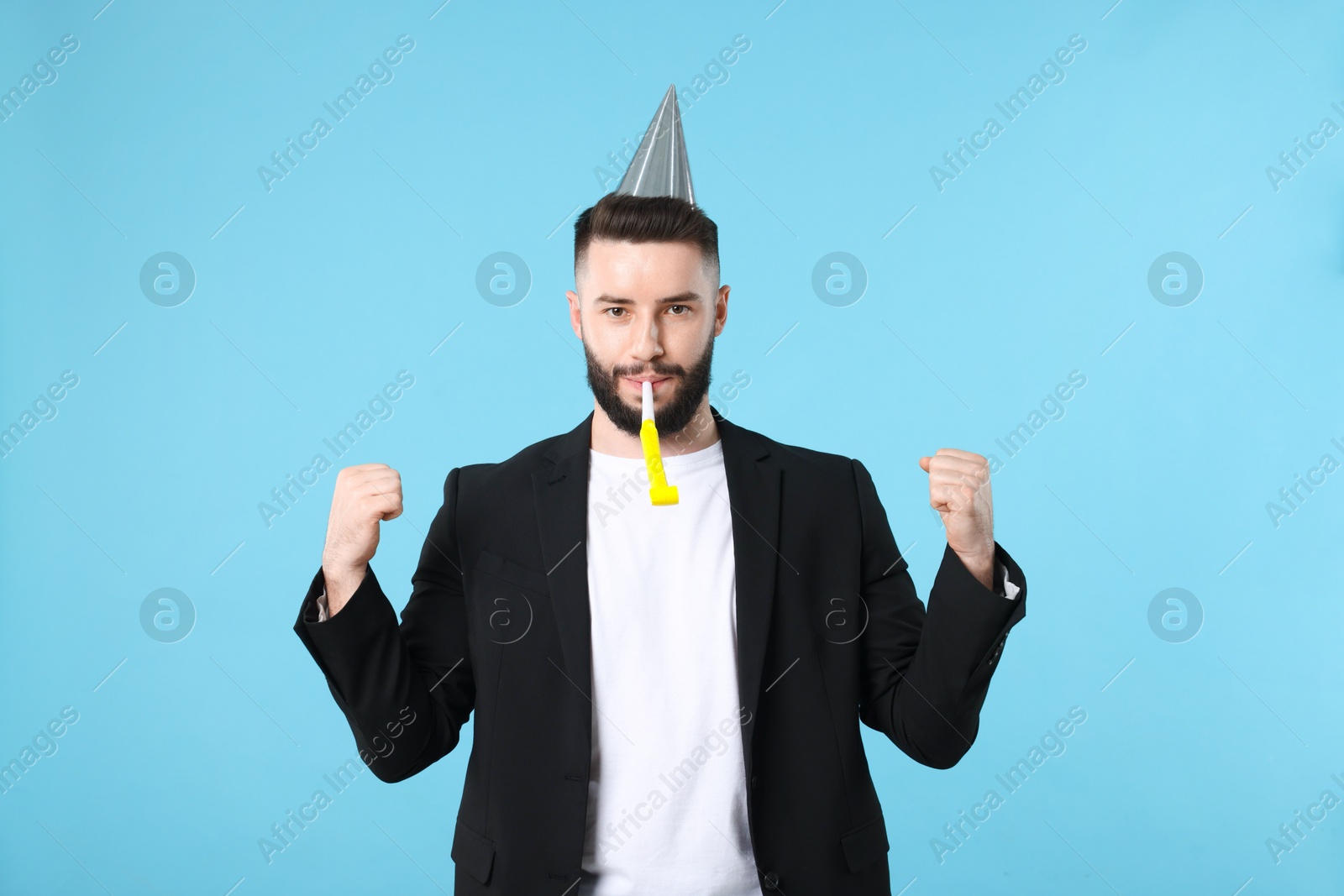 Happy Birthday. Handsome man with party hat and blower on light blue background Photo of Happy Birthday. Handsome man with party hat and blower on light blue background