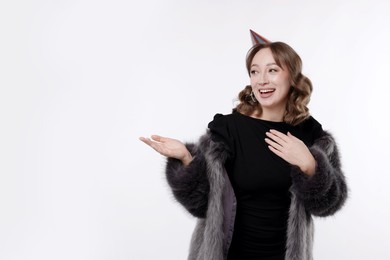 Photo of Birthday celebration. Happy woman pointing at something on white background. Space for text