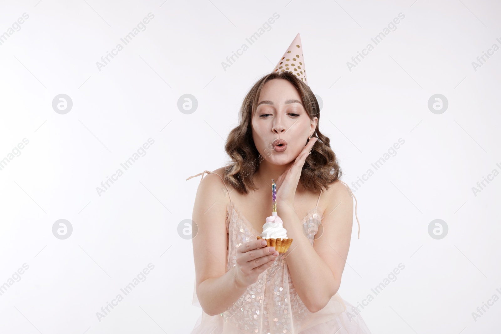 Birthday celebration. Woman blowing candle on cupcake against white background Photo of Birthday celebration. Woman blowing candle on cupcake against white background
