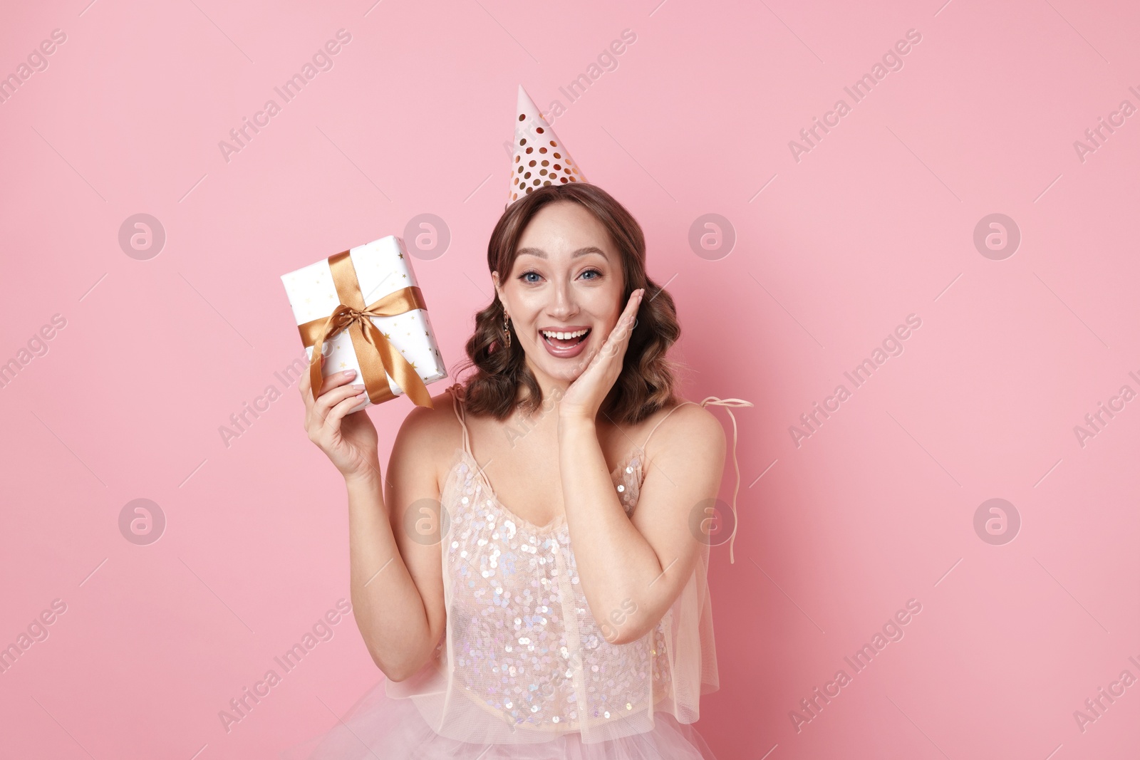 Birthday celebration. Woman with gift on pink background Photo of Birthday celebration. Woman with gift on pink background