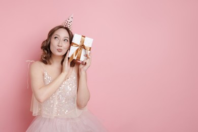 Photo of Birthday celebration. Woman with gift on pink background. Space for text