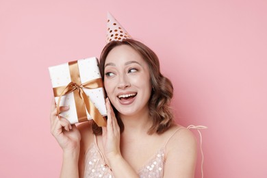 Photo of Birthday celebration. Woman with gift on pink background