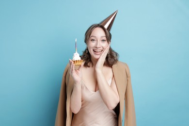 Photo of Birthday celebration. Woman with cupcake on light blue background
