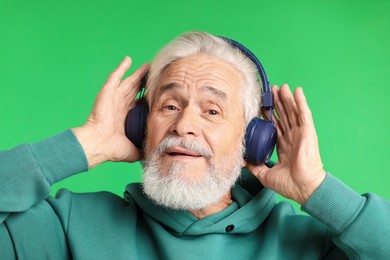 Photo of Elderly man in headphones on green background