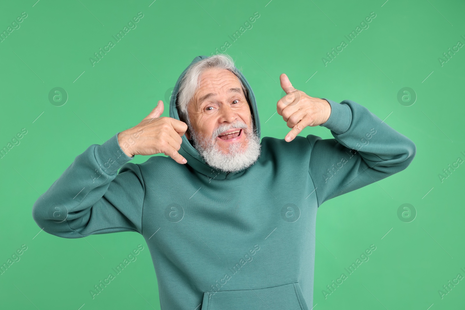 Elderly man in stylish outfit on green background Photo of Elderly man in stylish outfit on green background