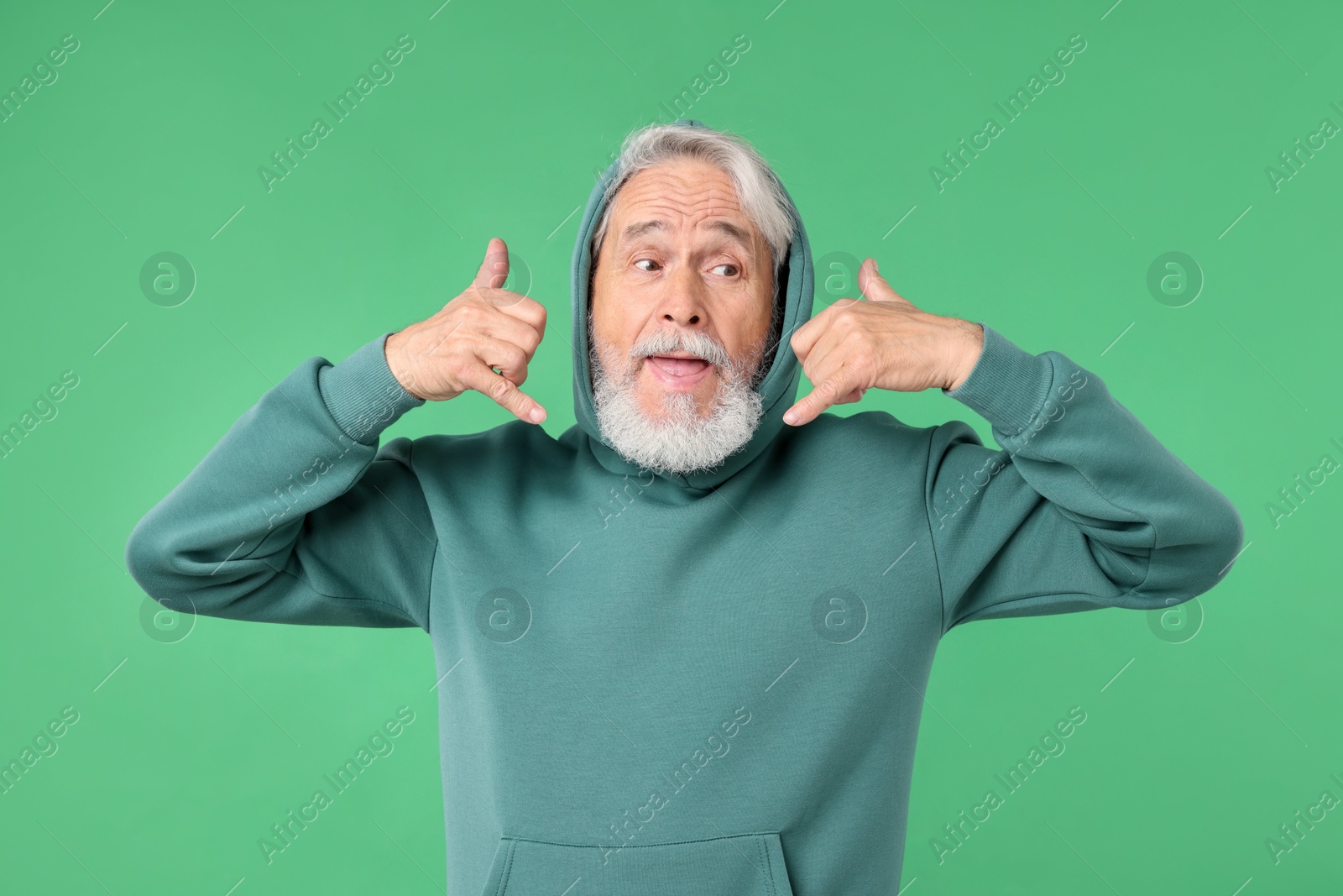 Elderly man in stylish outfit on green background Photo of Elderly man in stylish outfit on green background