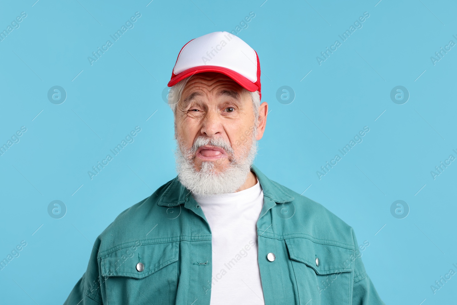 Elderly man in stylish outfit on light blue background Photo of Elderly man in stylish outfit on light blue background