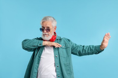 Photo of Elderly man in stylish outfit on light blue background