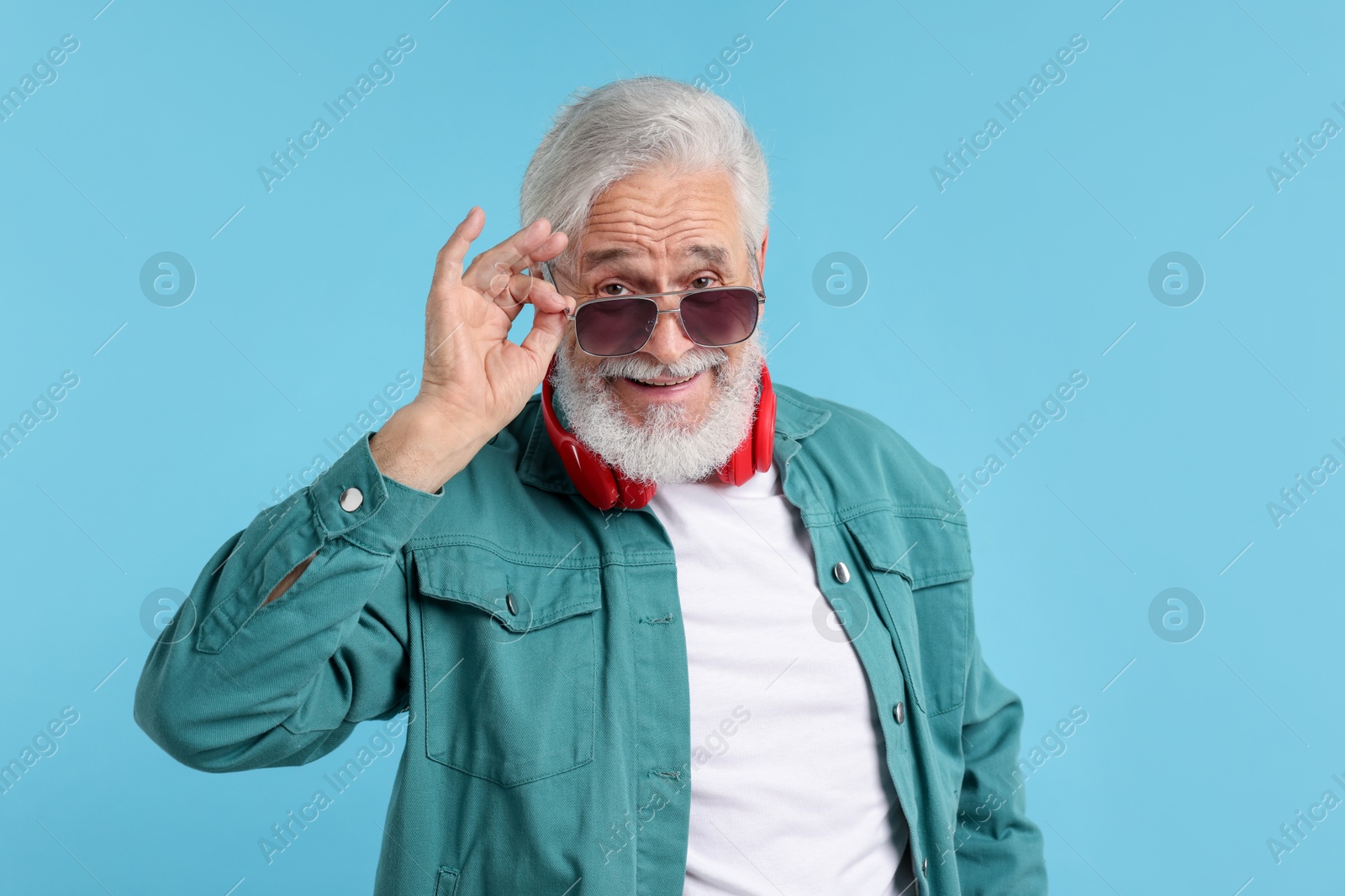 Elderly man in stylish outfit on light blue background Photo of Elderly man in stylish outfit on light blue background