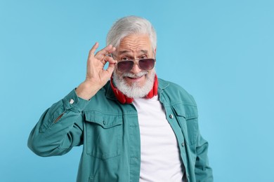 Photo of Elderly man in stylish outfit on light blue background