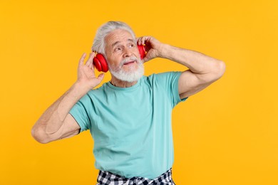 Photo of Elderly man with headphones on orange background