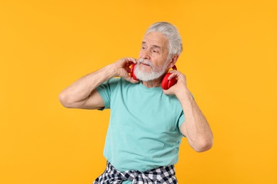 Photo of Elderly man with headphones on orange background