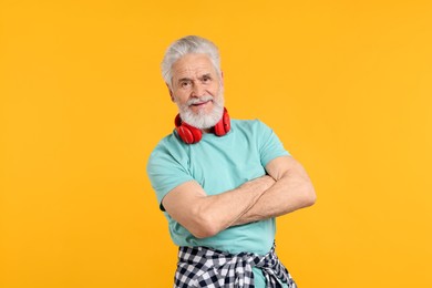 Photo of Elderly man with headphones on orange background